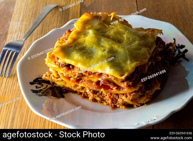 Traditional lasagna made with minced beef bolognese sauce and bechamel sauce topped with mozarella close up romantic rustic dinner