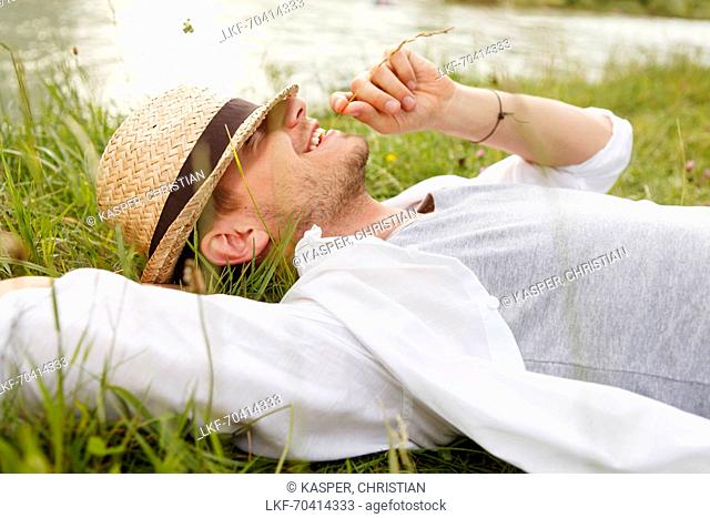 Young man lying on the Isar riverbank, Munich, Bavaria, Germany