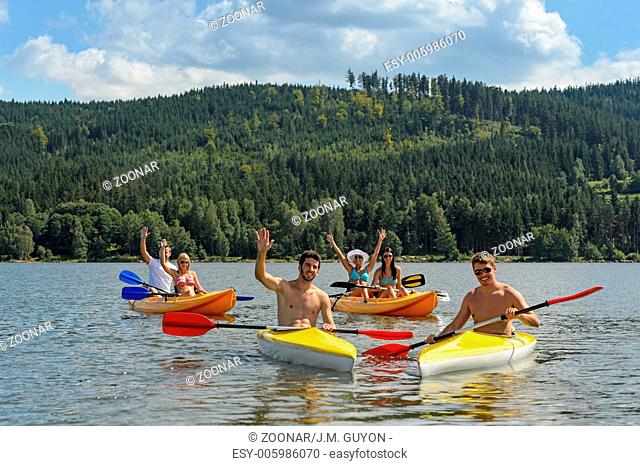 Waving cheerful friends in kayaks summer