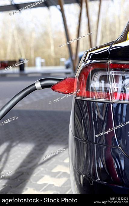 Rear view of a Tesla Model S charging at a charging station in Germany
