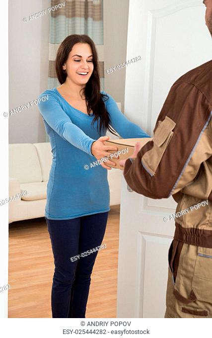 Smiling Young Woman Receiving Courier From Delivery Man At Home