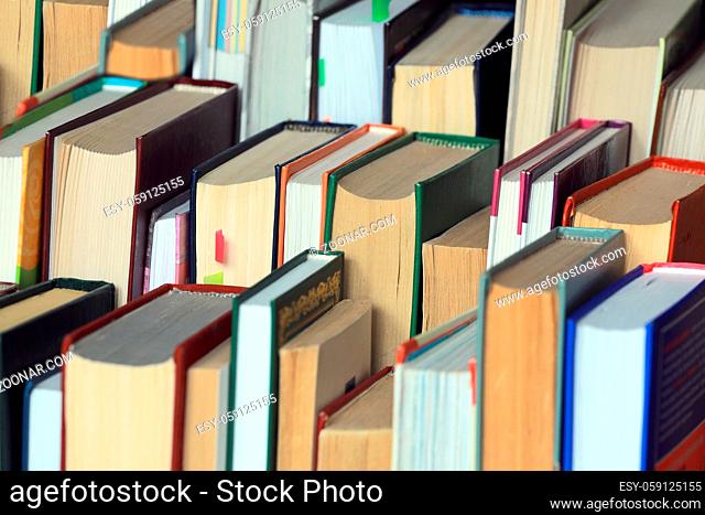 This is a lot of books standing together in several rows. Solid background of books in close-up. The concept of education and reading literature