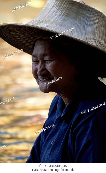 Damnoen Saduak Floating Market portrait of an old female vendor wearing a straw hat