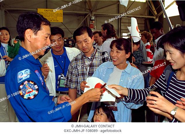 Astronaut Mamoru Mohri signs autographs for some members of the crowd who turned out for the STS-99 crew arrival at Ellington Field