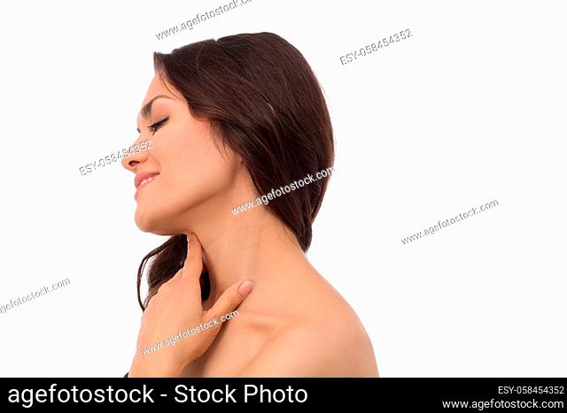 Pretty brunette woman standing half turn and gently touching her neck. beauty concept. Mid age woman over 35 years old beauty concept