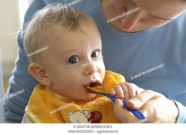 baby feeded with carrot mash by mother