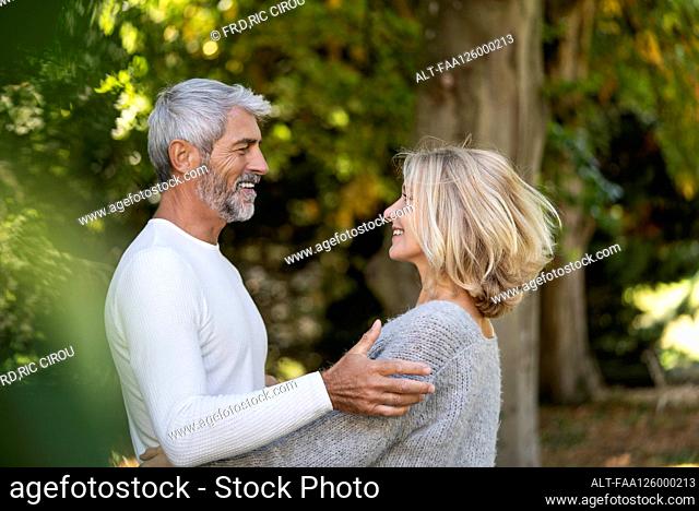 Side view of smiling mature couple looking at each other in backyard