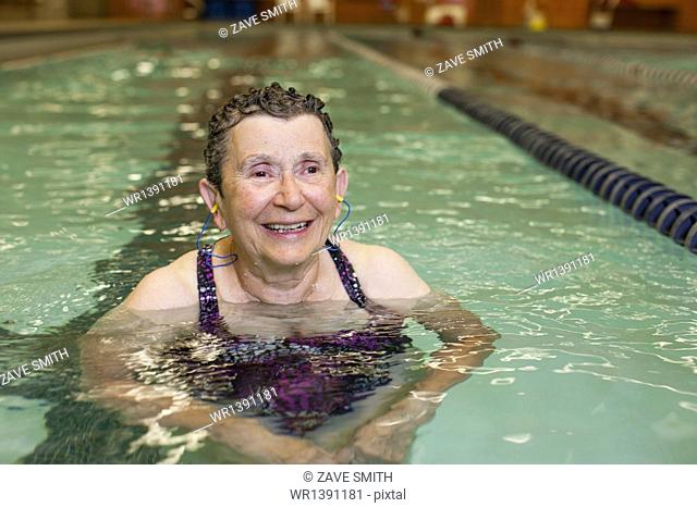 An elderly woman in a swimming pool, taking exercise