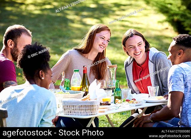 Smiling young friends having enjoying food in park