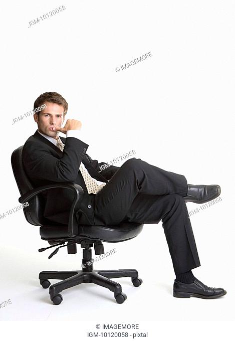 Businessman sitting on chair, looking at camera