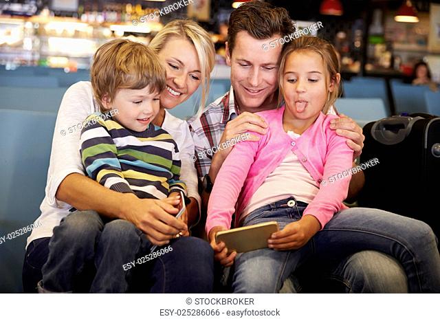 Family In Airport Departure Lounge Waiting To Go On Vacation