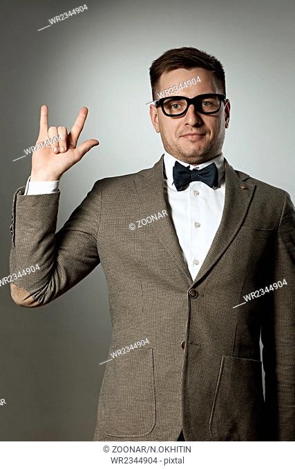 Nerd in eyeglasses and bow tie showing rock on gesture