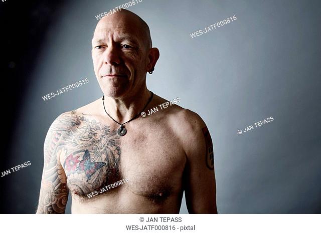 Portrait of bald man with tattoo on chest and arms