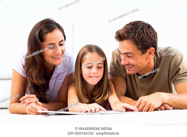 Family lying on a carpet with a book