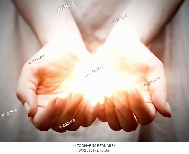 The light in young woman hands in cupped shape. Concepts of sharing