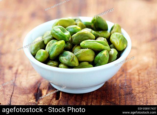 Pistachio Nuts In A White Bowl On A Wooden Background