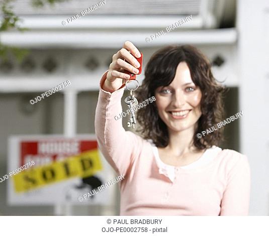 Woman with keys standing in front of house with sold sign