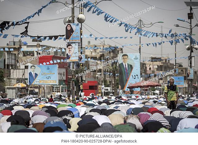 Iraqi men attend Friday prayers backdropped by campaign posters for the upcoming parliamentary elections in the Sadr City suburb of Baghdad, Iraq, 20 April 2018