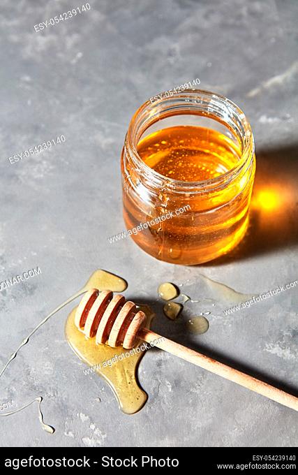 Jewish holiday Rosh Hashanah background with sweet organic honey on a gray concrete background, copy space. Top view. Traditional useful sweetness