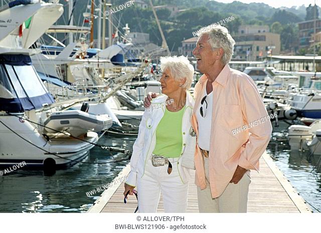 senior citizen couple on holiday strolling at harbour area