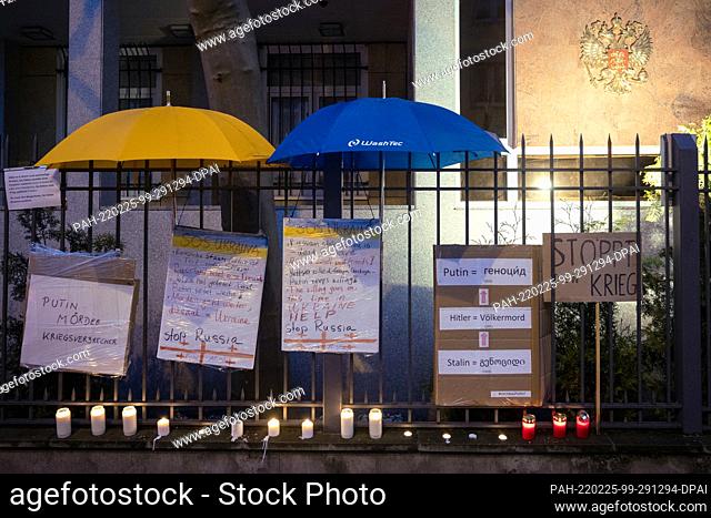 25 February 2022, Hessen, Frankfurt/Main: Signs and candles and umbrellas in blue and yellow are seen on the fence of the Russian Consulate General after people...