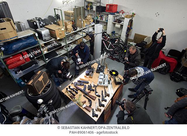 Journalists stand inbetween secured stolen goods from a robber's storage in the storage room of the police department in Dresden, Germany, 16 March 2017