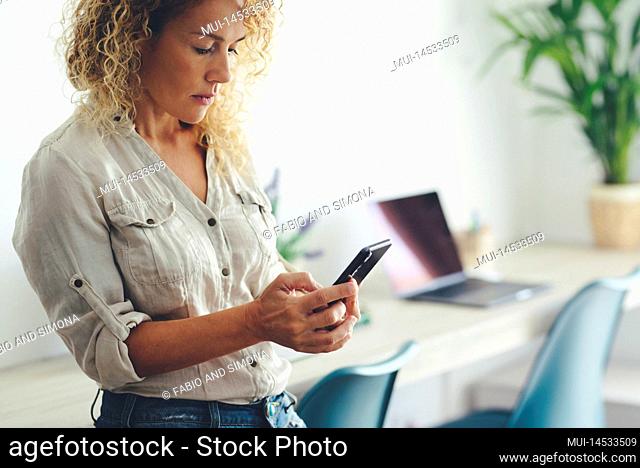 Pretty young adult woman sending message on mobile phone. Concept of social connection with smartphone. Female people using technology at office