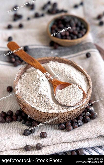 Bowl of black chickpea flour and beans with a wooden spoon closeup on white wooden table. Traditional beans from Apulia and Basilicata in Italy