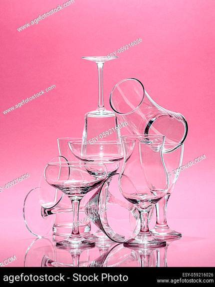 Composition of glass glasses of different shapes on a rose background. Art photo in pastel colors