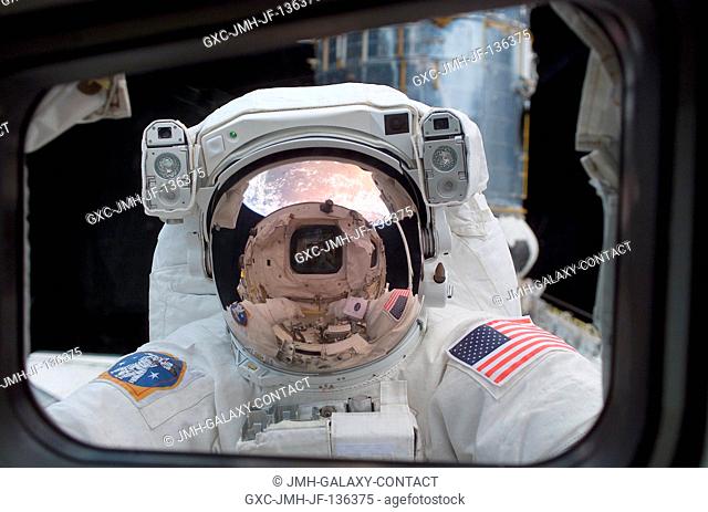 Astronaut John M. Grunsfeld, payload commander, peers into the crew cabin of the Space Shuttle Columbia during the first STS-109 extravehicular activity (EVA-1)...