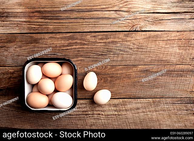 Flat lay with metal can basket full of organic chicken eggs on wooden background. Organic household concept with eggs from free-range and pasture raised hens