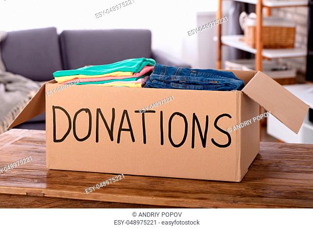 Close-up Of Clothes In Donation Box On Wooden Desk