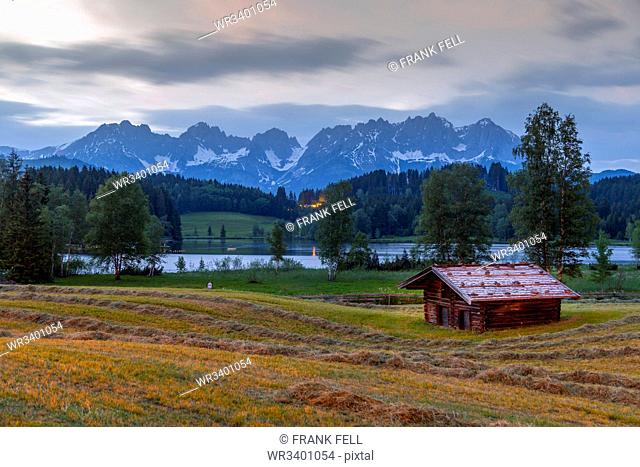 View of traditional log cabin and Kaiser Mountain Range backdrop at Schwarzsee near Kitzbuhel, Tyrol, Austria, Europe