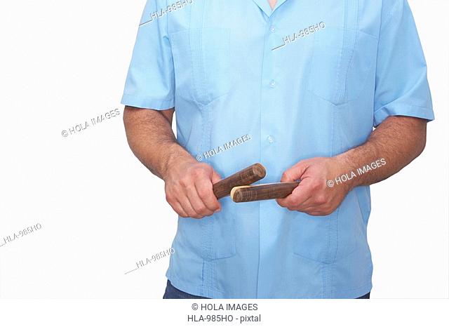 Mid section view of a man holding a pair of claves