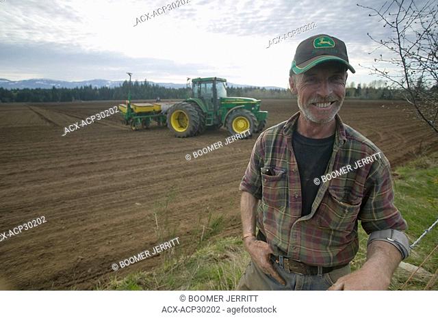 A farmer planting corn takes a break from his tractor to refuel and give his legs a chance to stretch. Courtenay, The Comox Valley, Vancouver Island