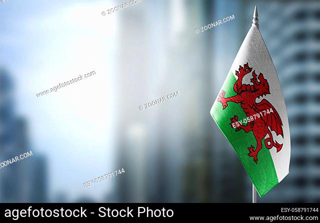 A small flag of Wales on the background of an urban abstract blurred background