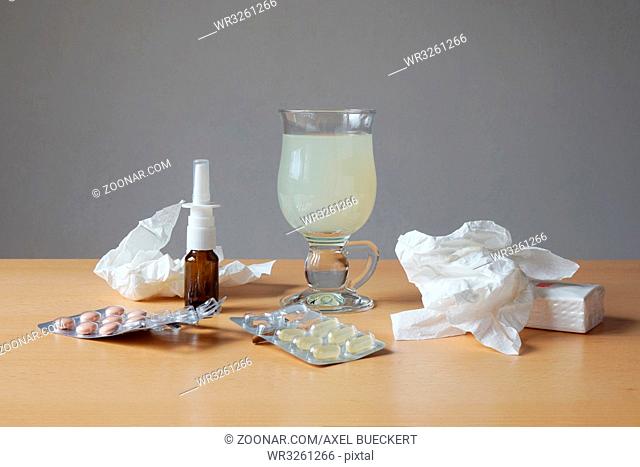 common cold or flu remedy. hot lemonade, nasal spray, pills, and tissues