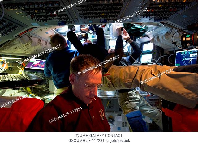While his crewmates take pictures out overhead windows, NASA astronaut Chris Ferguson (foreground), commander, consults a check list (out of frame)right...