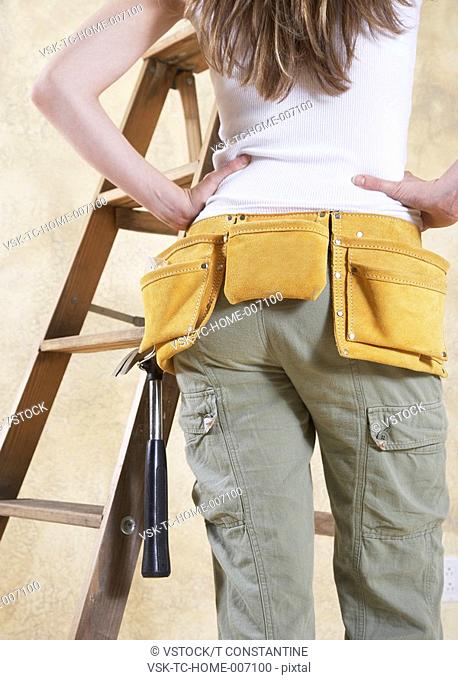 Woman wearing tool belt, mid section, rear view