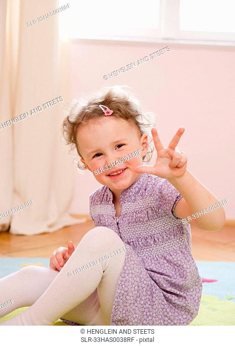 Smiling girl holding up three fingers