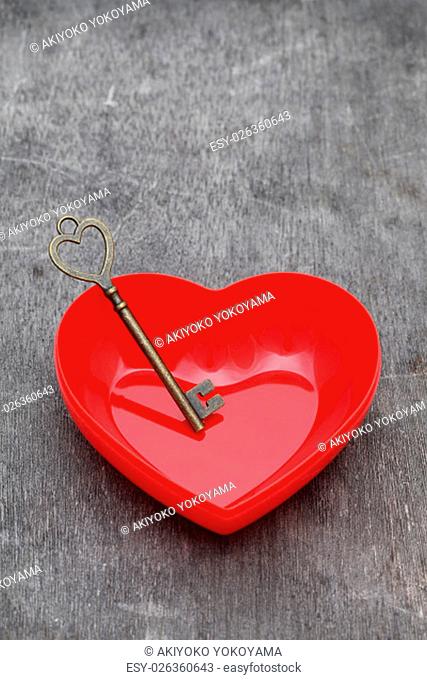 vintage key and red heart on grunge wooden background