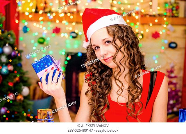 Young beautiful girl sitting at a table with Christmas gifts in the Christmas atmosphere