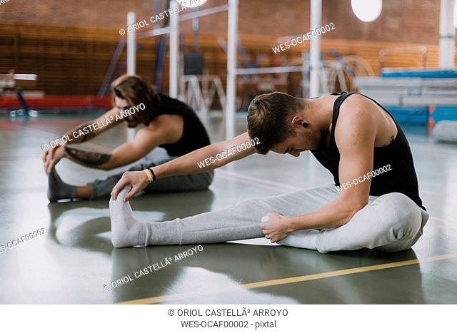 Two young men stretching in gym