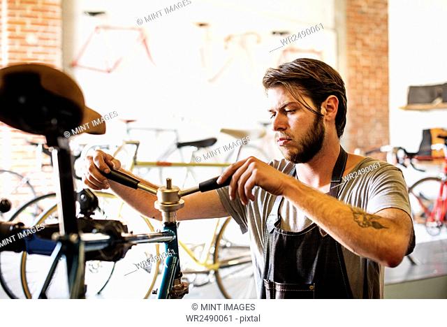 A man working in a bicycle repair shop, checking the frame of the bike