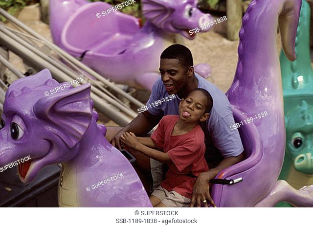 High angle view of a father with his son riding an amusement park ride
