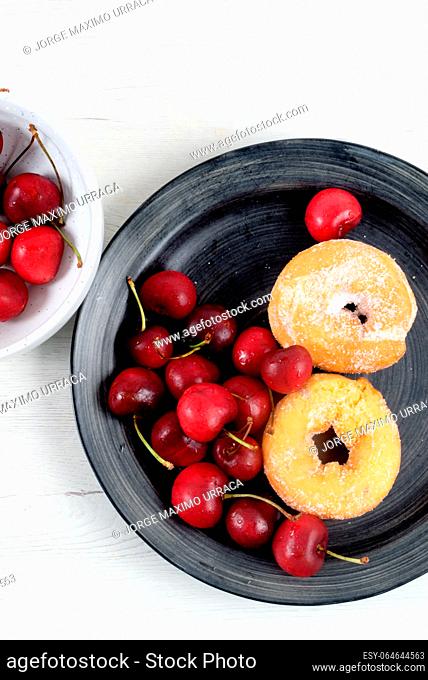Dish with delicious doughnuts and cherries