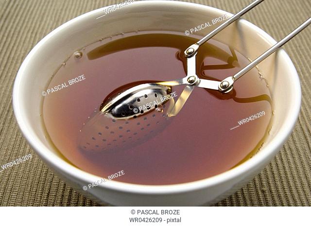 Close-up of a bowl of tea with a sieve