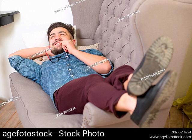 Handsome man reclining comfortably on a couch while talking to his psychiatrist and explaining something
