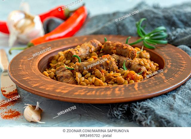 Plate with spicy green lentils with sausages on textured white table, selective focus