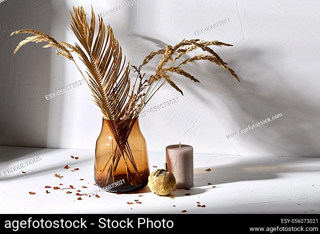 dried flowers in glass vase candle and pumpkin